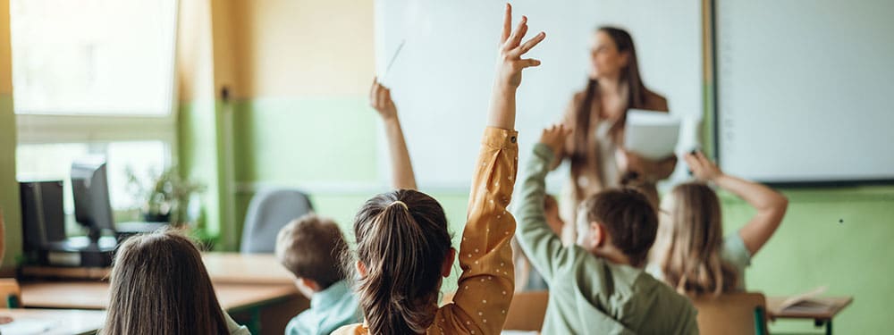 Students eagerly participate in class by raising their hands to answer questions and engage in discussions