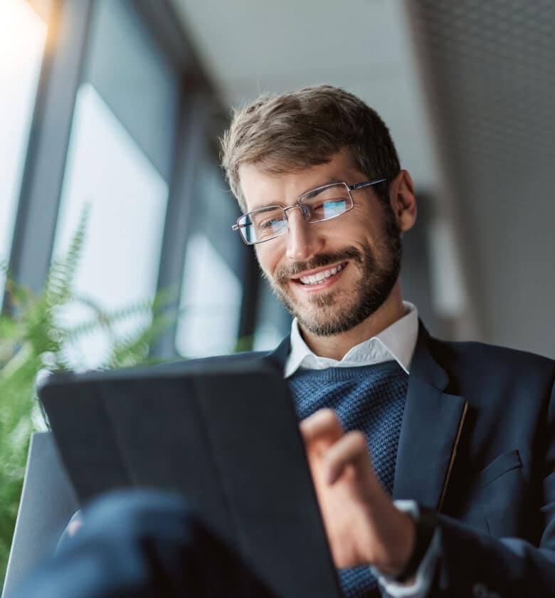 A man wearing glasses using a tablet computer