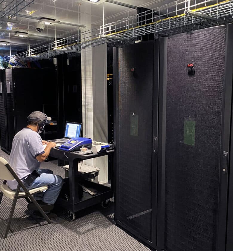 IT expert with a laptop is working in a server room