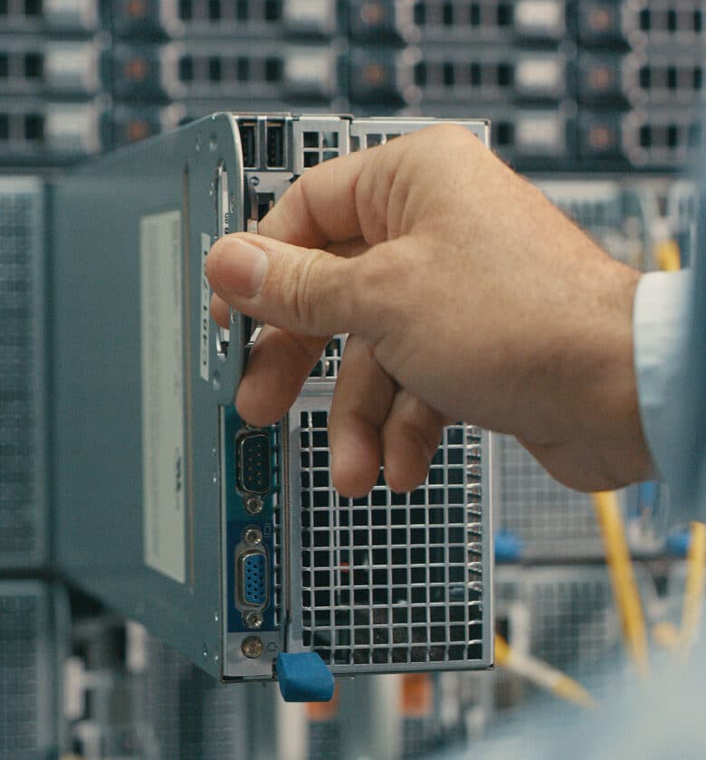 A person holding a computer in front of a server