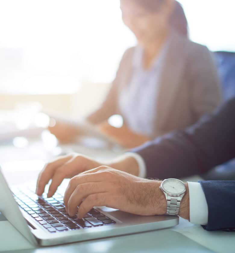 A businessman in a suit typing on a laptop