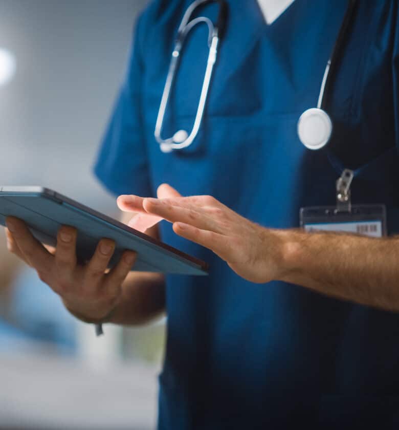 Doctor wearing blue scrubs and holding a tablet