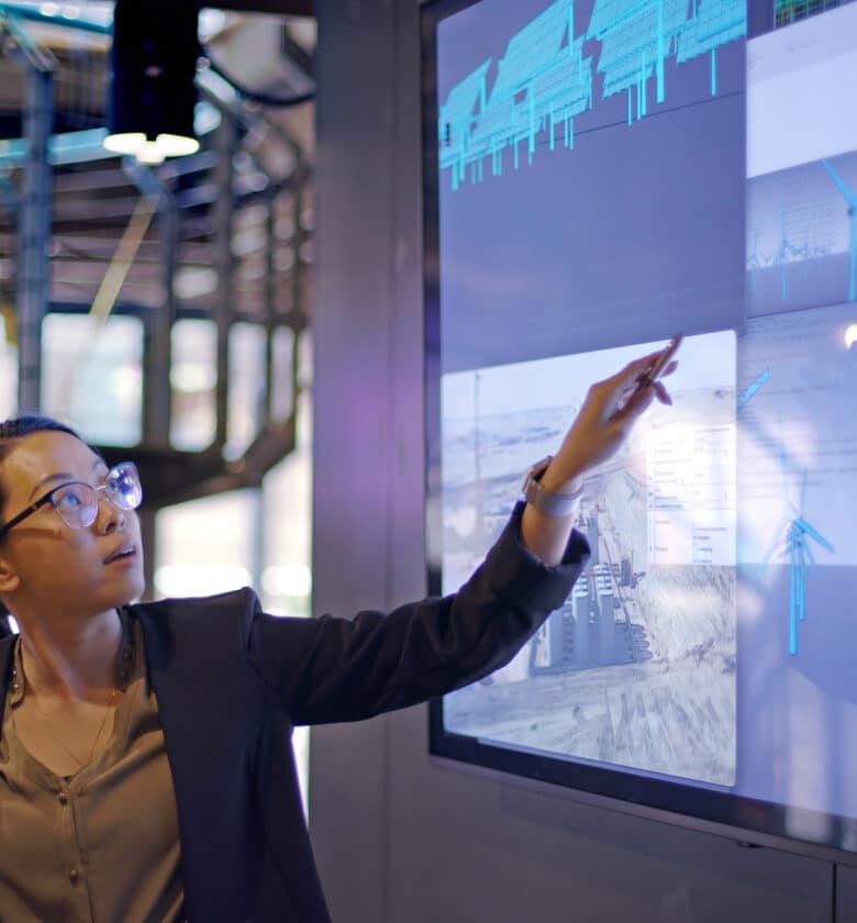 A woman gesturing towards data visualizations on a screen