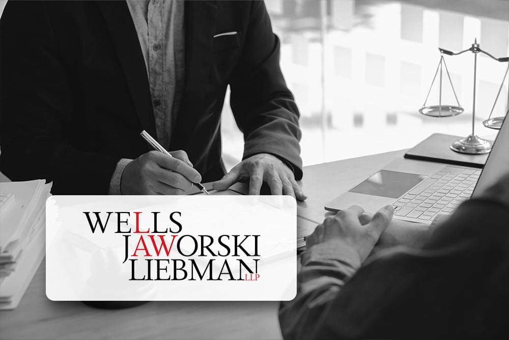 An attorney in a professional office setting, using a laptop and holding a pen