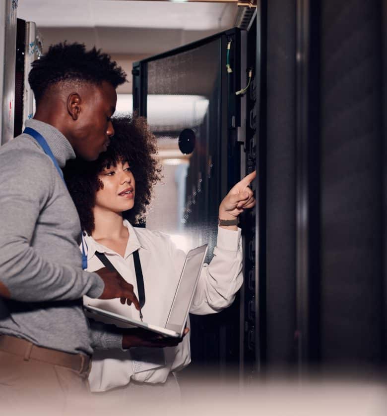 Two individuals using a computer in a server room