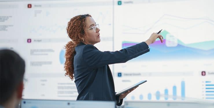 a woman in a business suit gesturing towards a chart