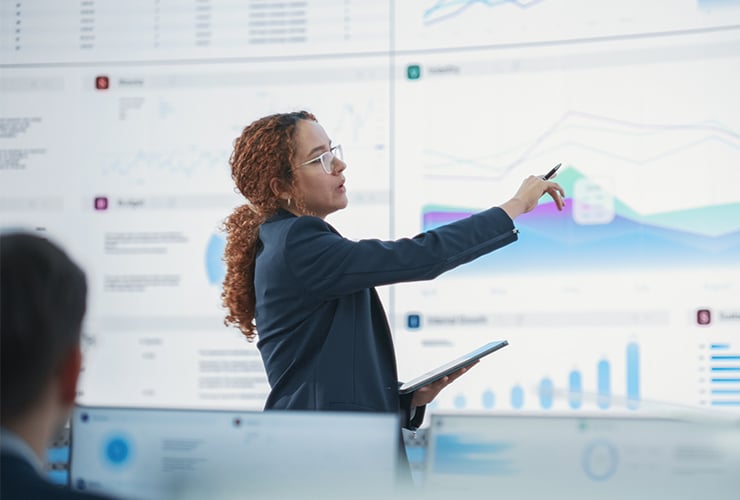a woman in a business suit gesturing towards a chart